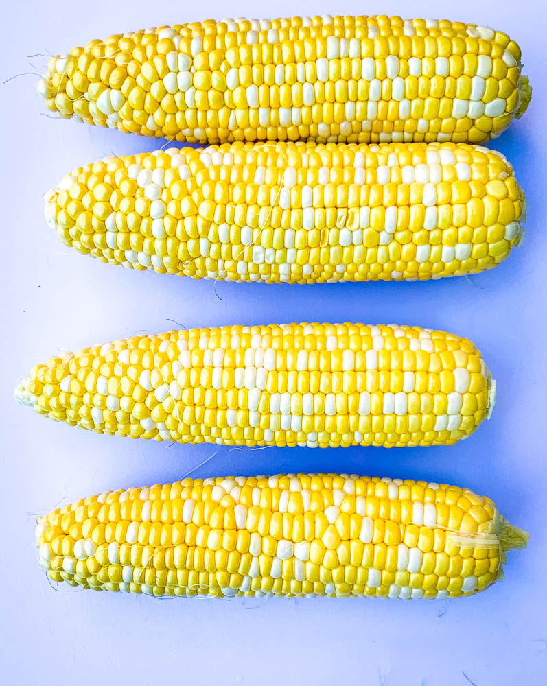 raw shucked corn on the cob on a cutting board