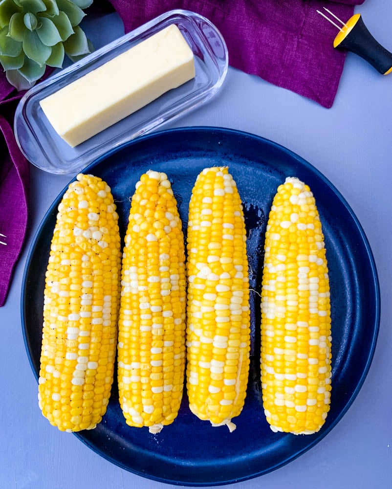 instant pot corn on the cob on a blue plate with a purple napkin. 