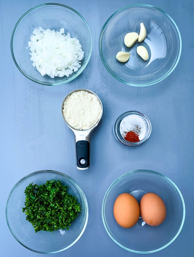 ingredients for keto low carb meatloaf chopped onions, garlic cloves, eggs, and parsley