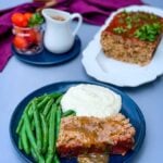 sliced keto low carb meatloaf on a blue plate with mashed cauliflower and blanched green beans