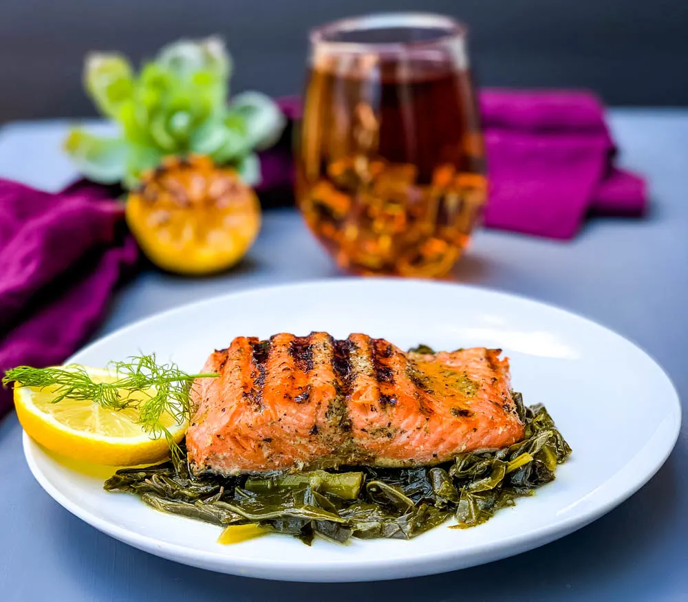 pan seared cast iron salmon on a white plate with greens