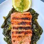 pan seared cast iron salmon on a white plate with greens