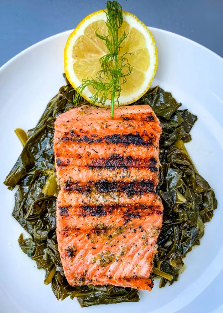 pan seared cast iron salmon on a white plate with greens
