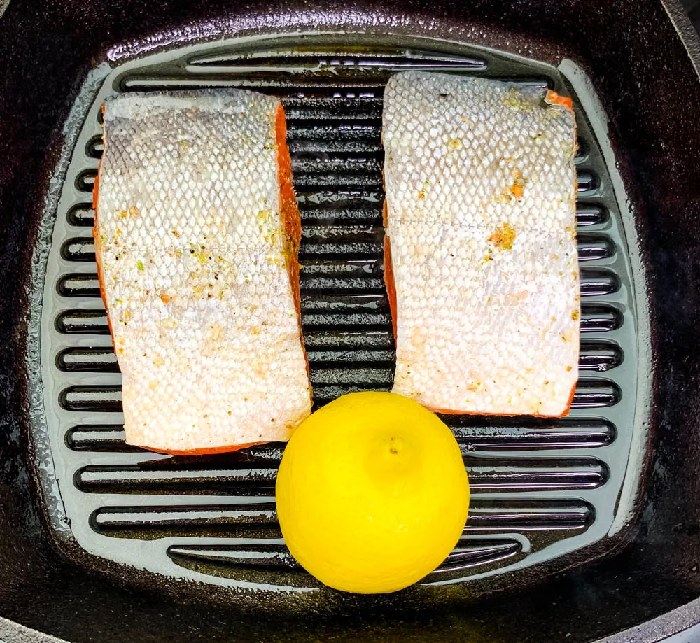 pan seared salmon in a cast iron grill pan skillet with lemon