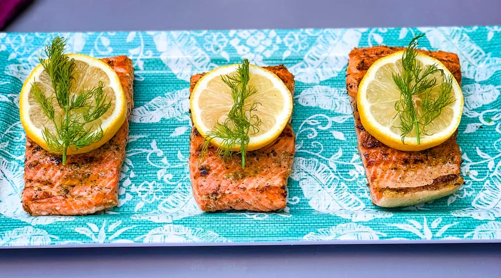 pan seared cast iron salmon on a blue plate with greens