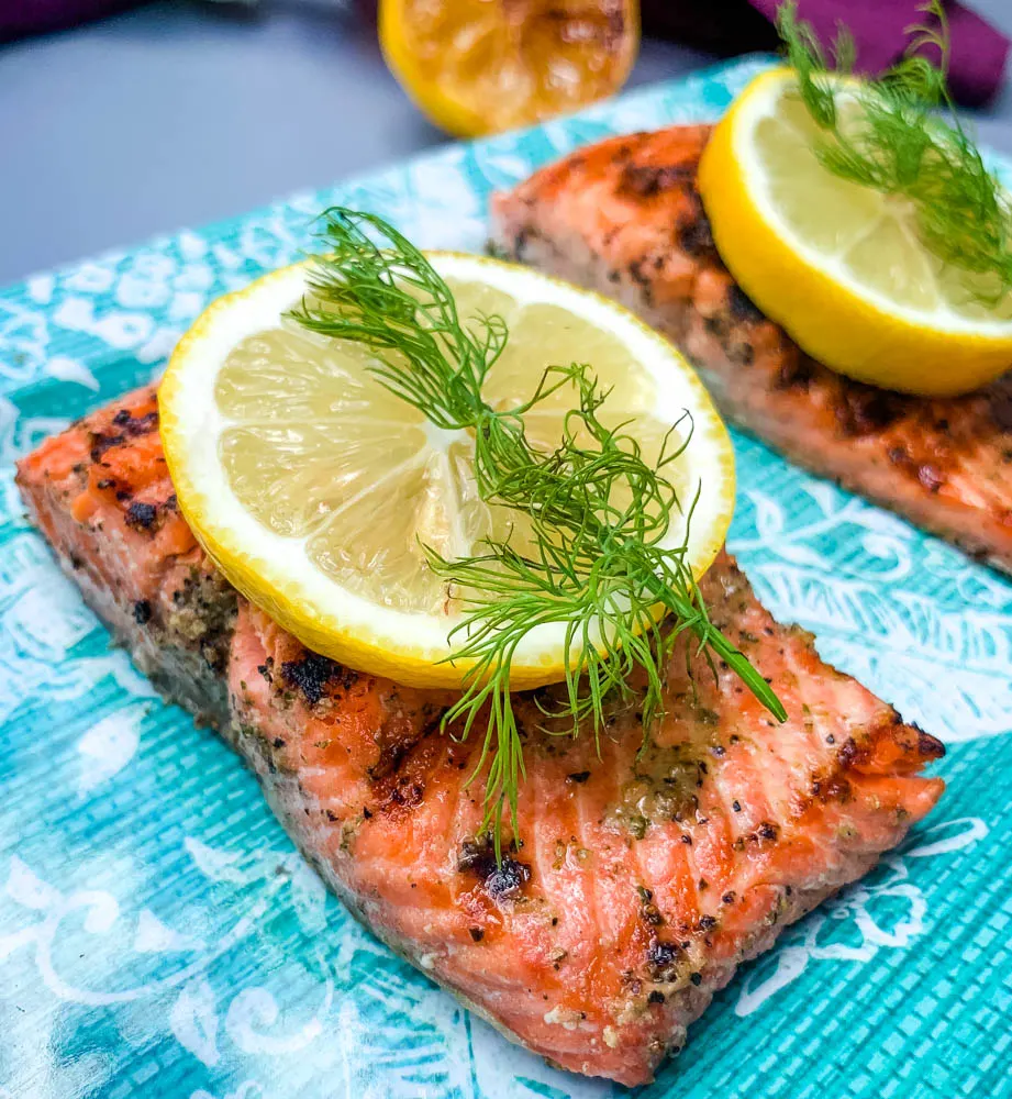 pan seared cast iron salmon on a blue plate with greens