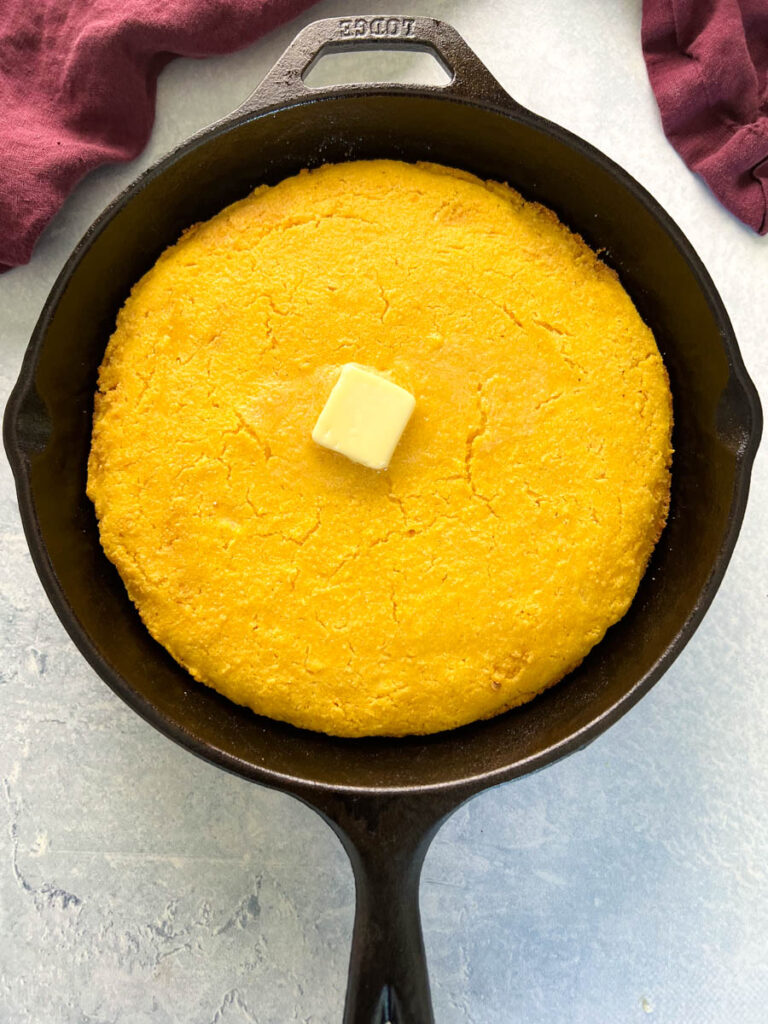baked cornbread in a cast iron skillet with butter on top