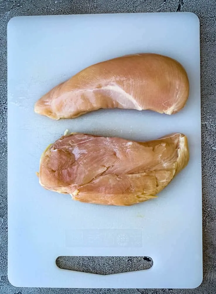 raw chicken breasts on a cutting board