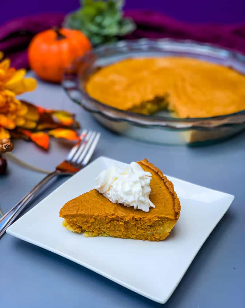 keto low carb pumpkin pie on a white plate with a whole cut pie in the back