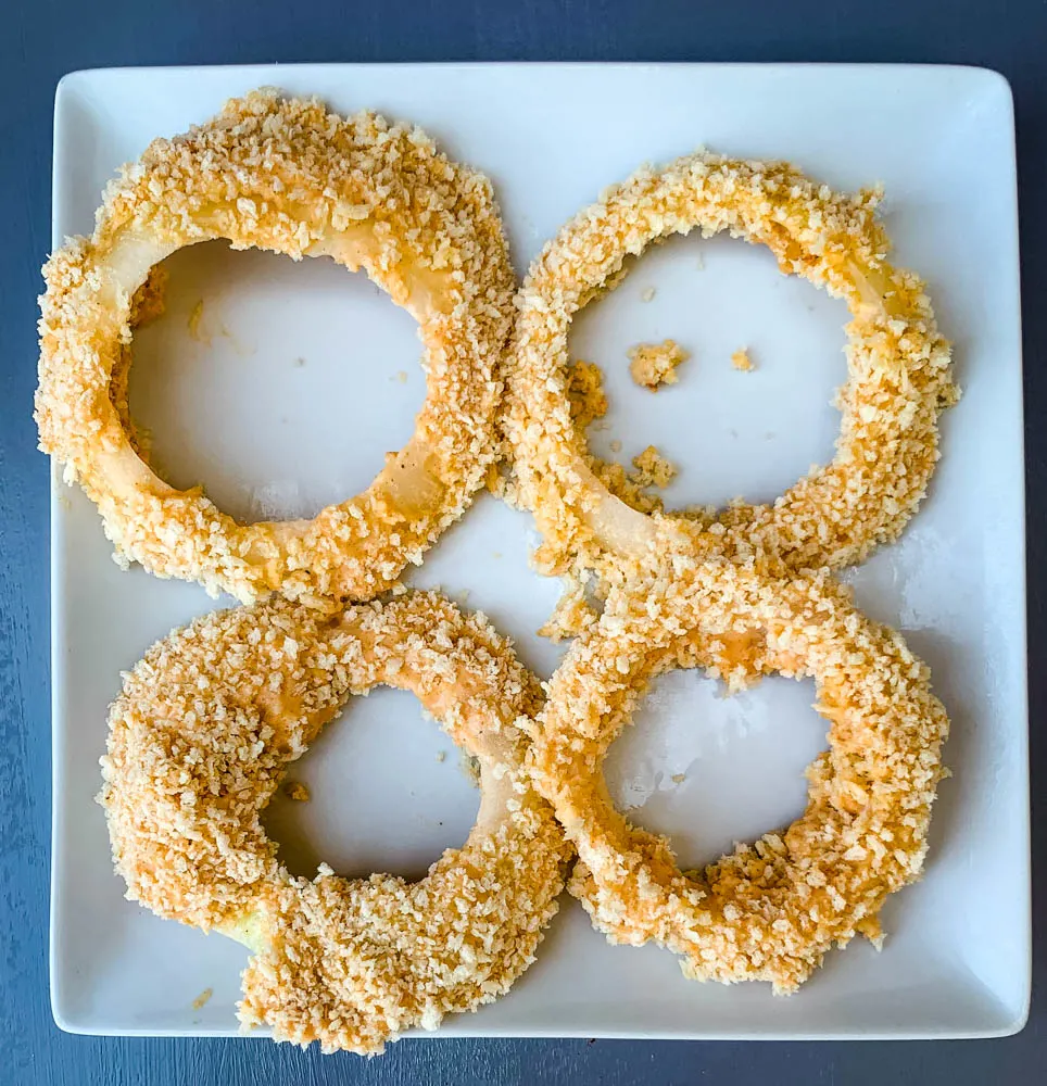 battered uncooked air fryer onion rings on a white plate
