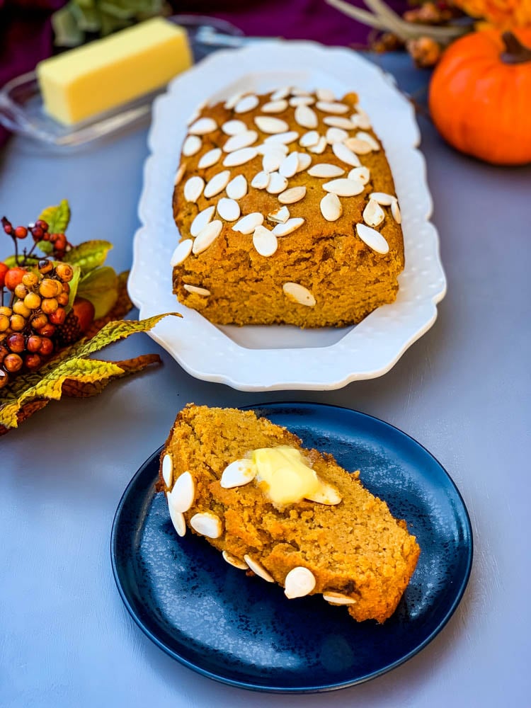 keto low carb pumpkin bread on a white plate with a slice of pumpkin bread on a blue plate