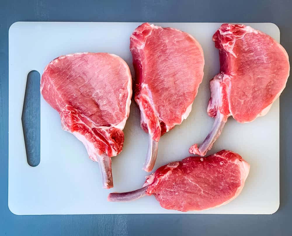 raw bone in pork loin chops on a cutting board