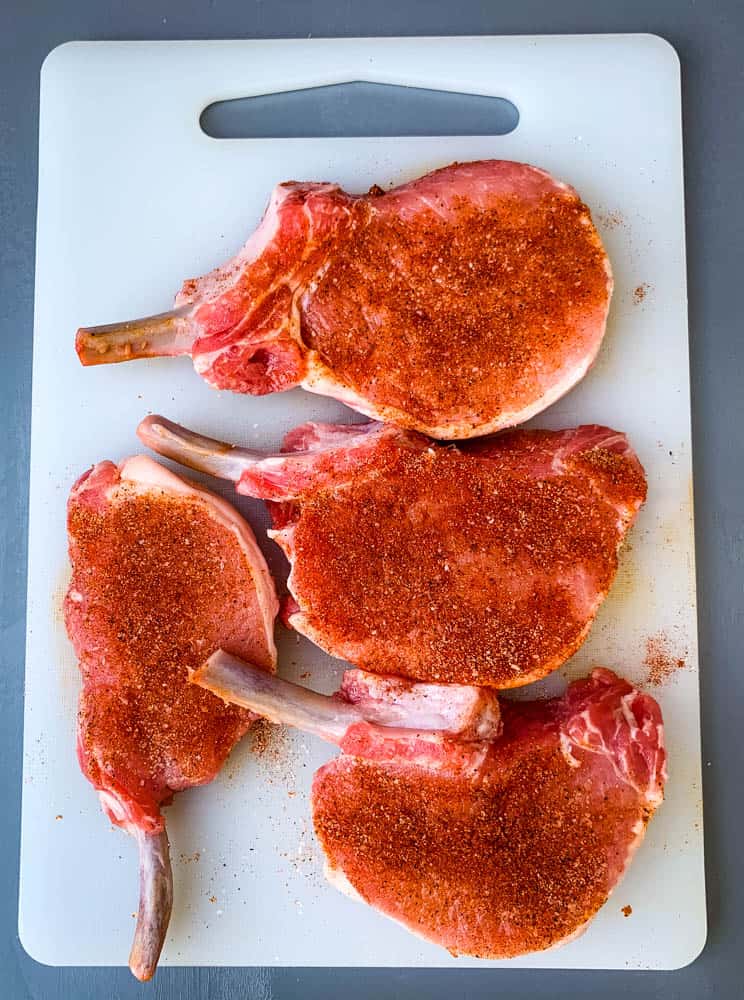 raw seasoned pork loin chops on a cutting board