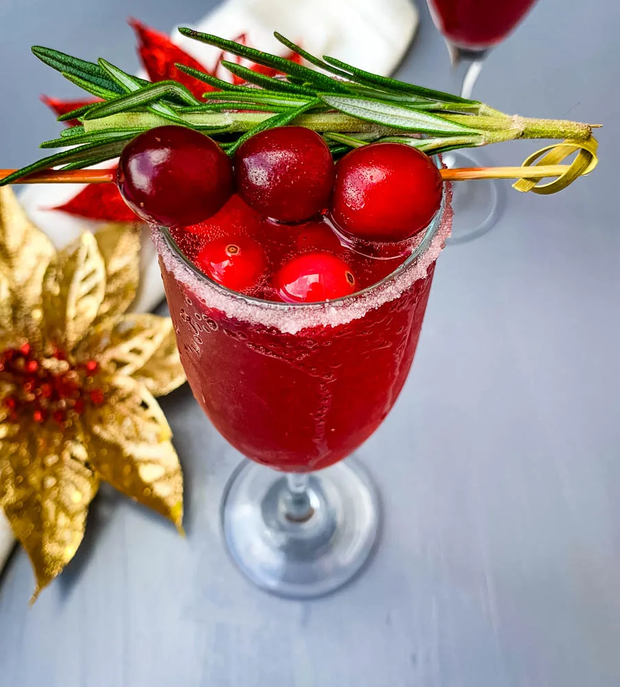 cranberry champagne mimosa in a glass with fresh cranberries