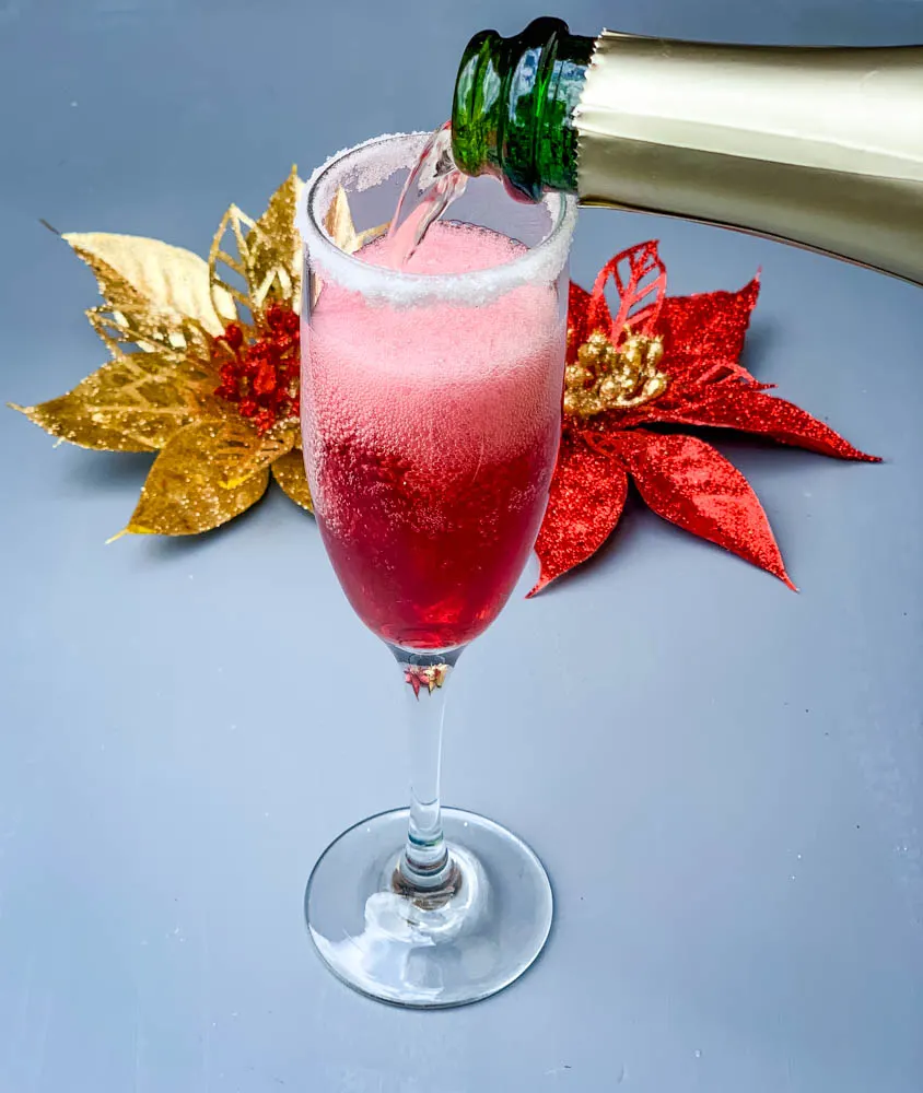 a pour of champagne into a cranberry mimosa