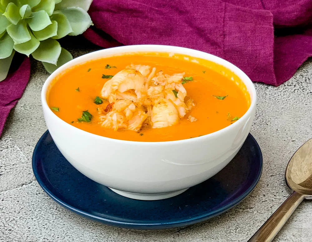 creamy homemade lobster bisque recipe in a white bowl with a purple towel