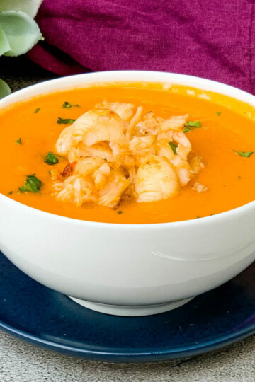 creamy homemade lobster bisque recipe in a white bowl with a purple towel