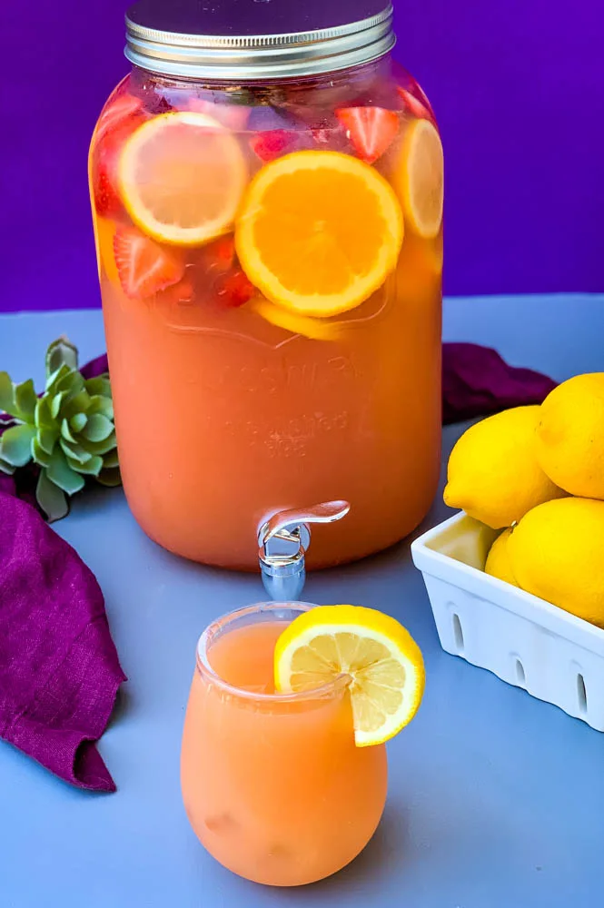 jungle juice cocktail recipe in a 2 gallon glass container with fresh fruit