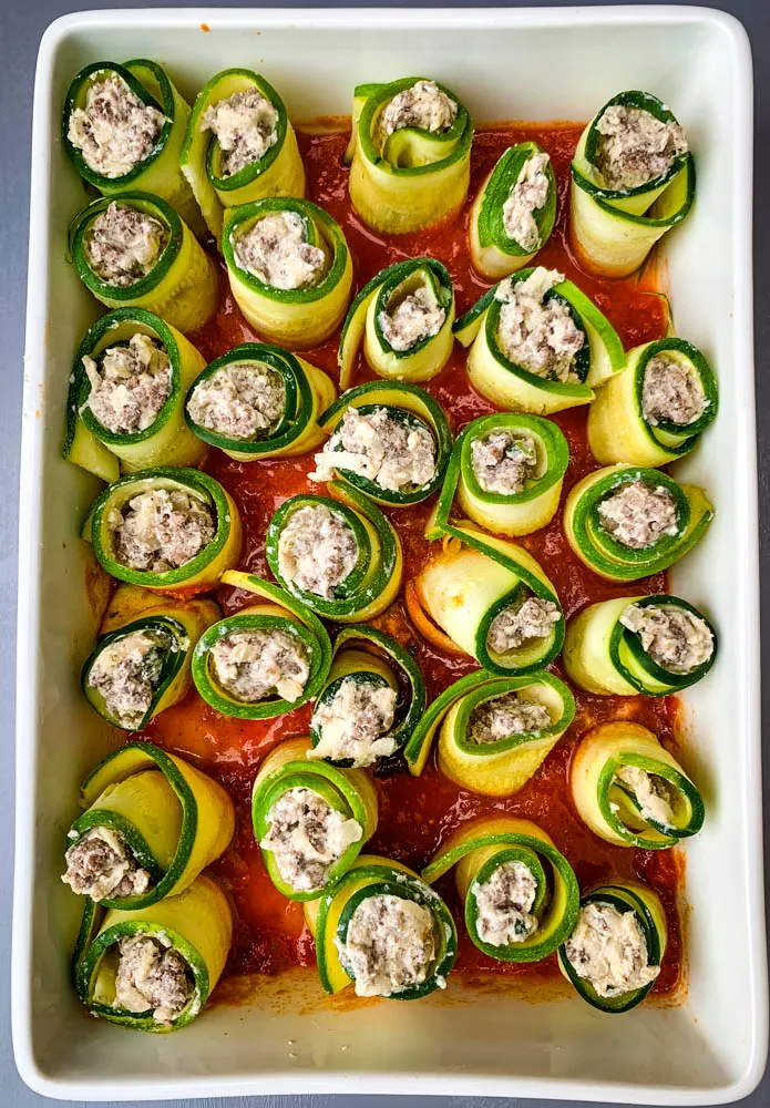 zucchini lasagna rolls in a white baking dish