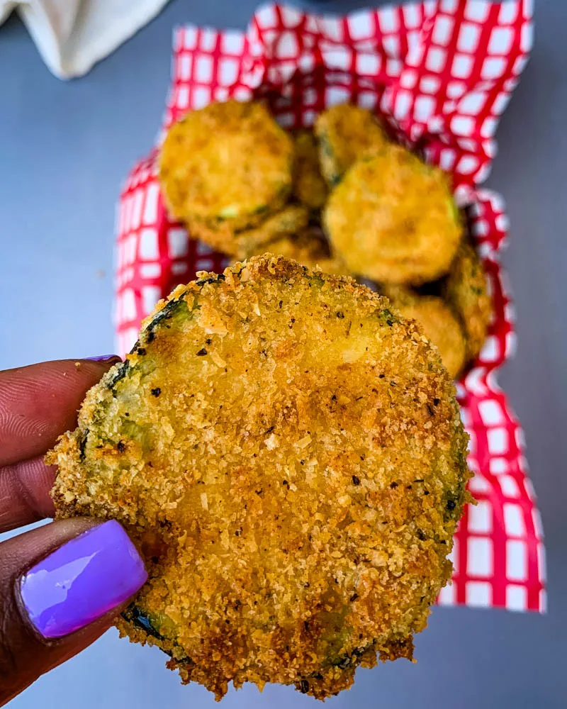 person holding air fryer zucchini chip
