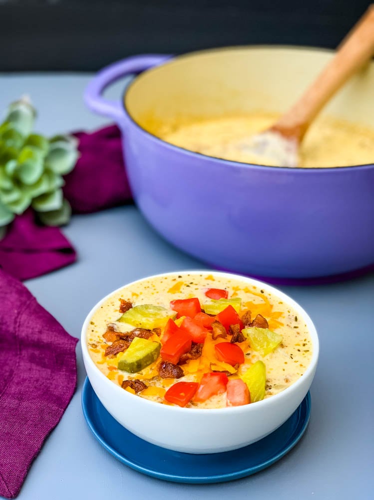 keto low carb cheeseburger soup in a white bowl with pickles, tomatoes, and bacon