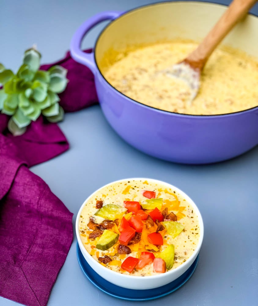 keto low carb cheeseburger soup in a white bowl with pickles, tomatoes, and bacon