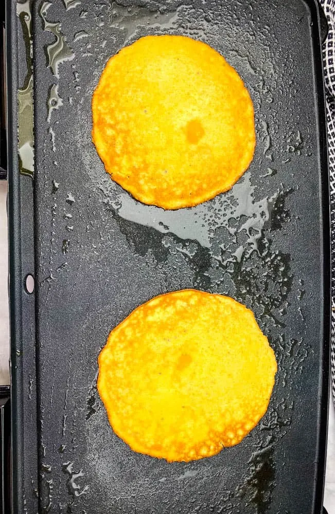 keto low carb pancakes cooking on a griddle