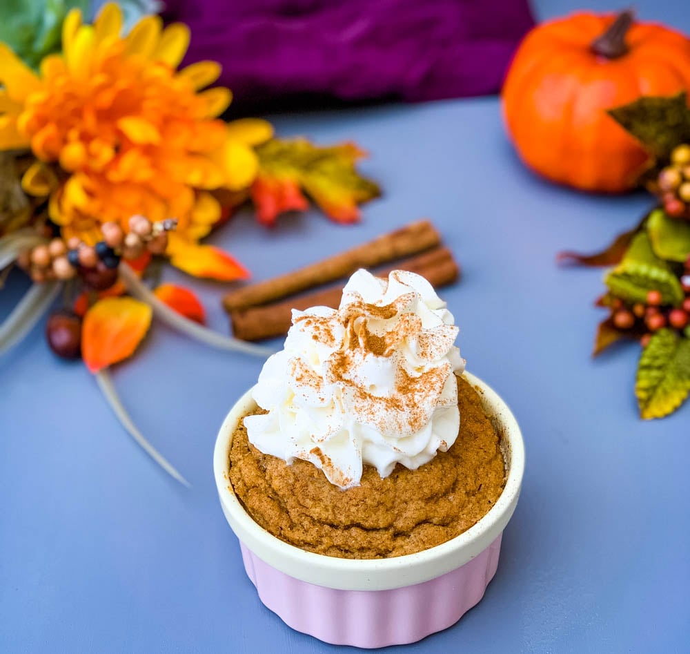 keto low carb pumpkin mug cake in a pink ramekin with whipped cream