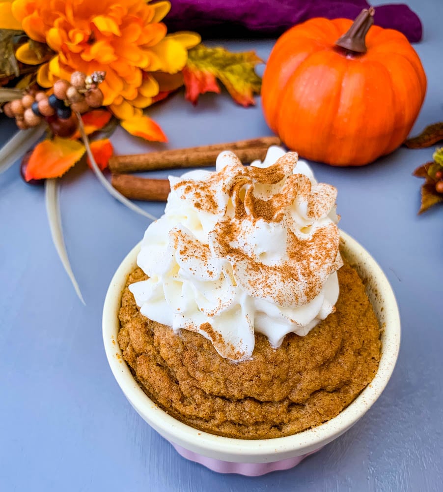 keto low carb pumpkin mug cake in a pink ramekin with whipped cream