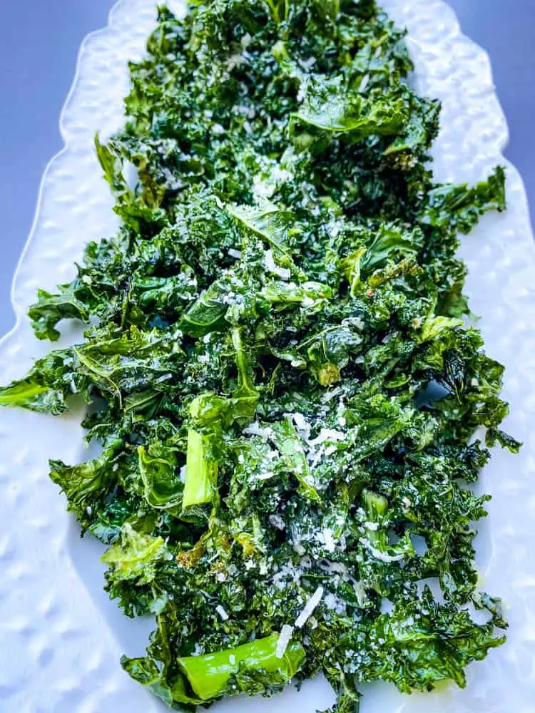 air fryer kale chips on a white plate with parmesan cheese