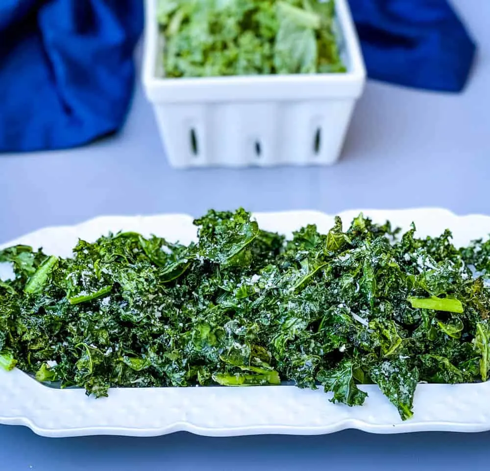 air fryer kale chips on a white plate with parmesan cheese