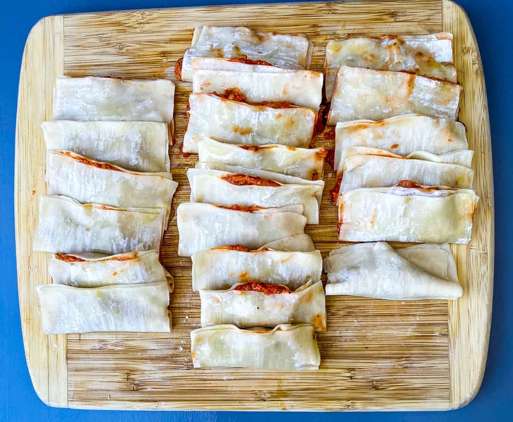 pizza rolls in wonton wrappers on a bamboo cutting board