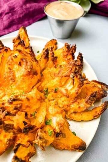 air fryer blooming onion on a plate with sliced lemons