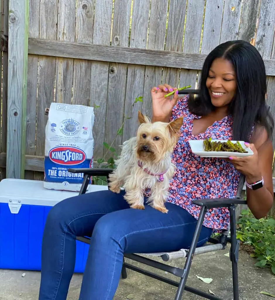 person eating asparagus with a dog on their lap