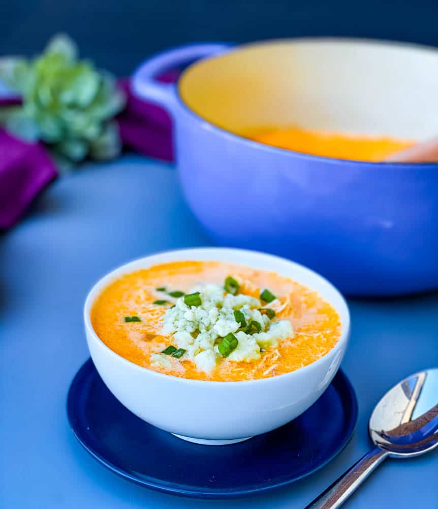 buffalo chicken soup in a white bowl with a spoon and a pot of soup