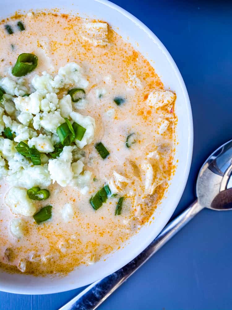 buffalo chicken soup in a white bowl with blue cheese and green onions