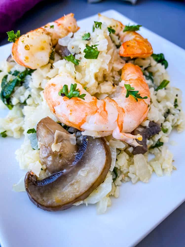 keto low carb cauliflower risotto on a white plate with lemon and shrimp