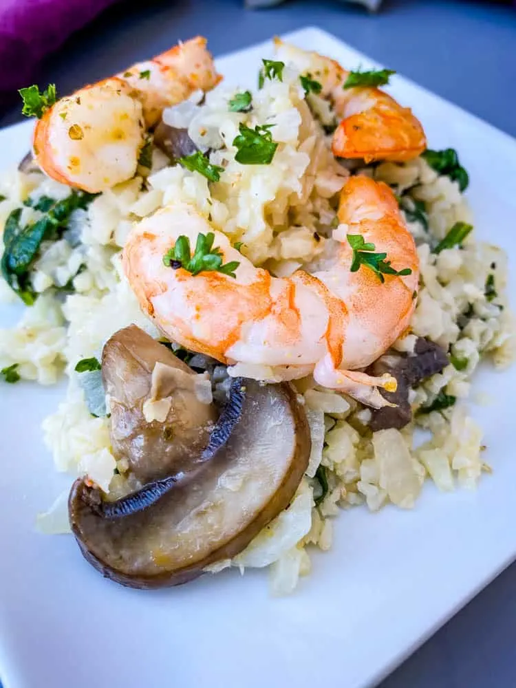 keto low carb cauliflower risotto on a white plate with lemon and shrimp