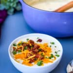 keto low carb cauliflower soup in a white bowl with shredded cheese and bacon
