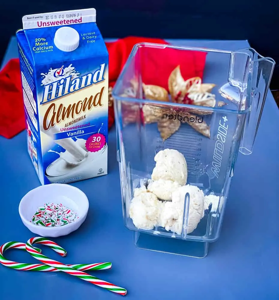 ice cream in a blender with a carton of almond milk for peppermint milkshakes