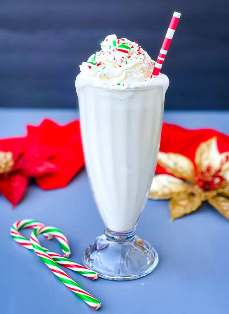 peppermint milkshake with candy canes and whipped cream in a glass with a straw