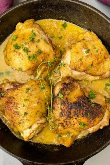 smothered pork chop thighs in a cast iron skillet with gravy