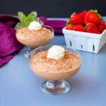 keto low carb chocolate mousse in a glass bowl with a white bowl of fresh strawberries