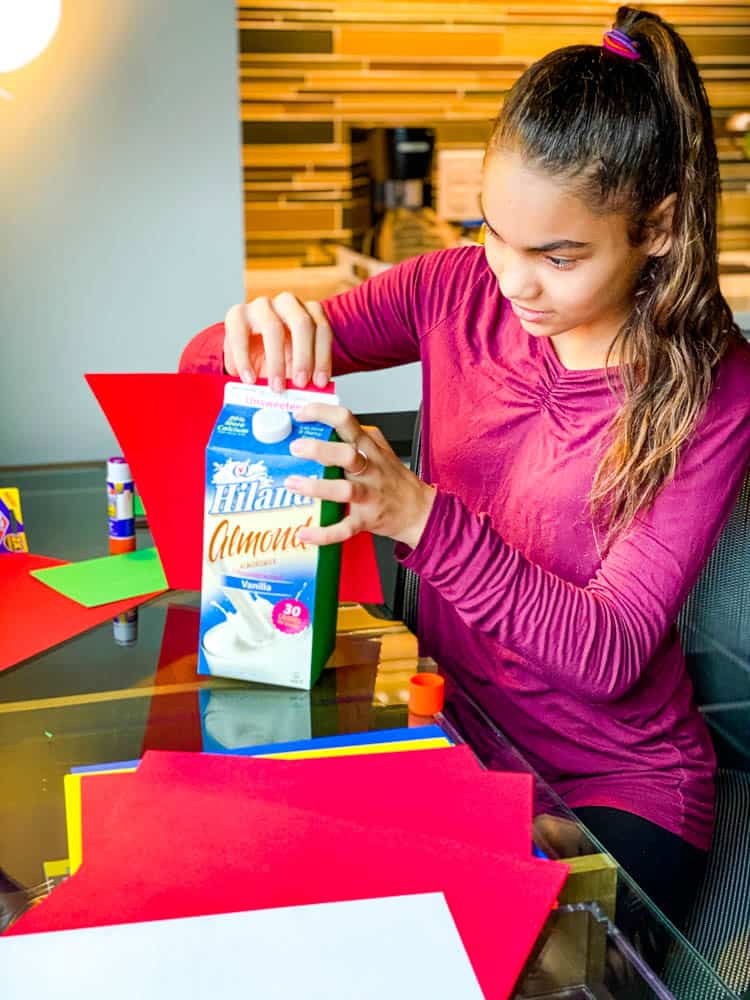 child making Christmas decoration using recycled milk carton