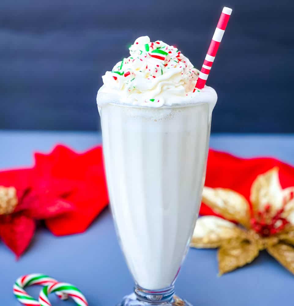 peppermint milkshake with candy canes and whipped cream in a glass with a straw