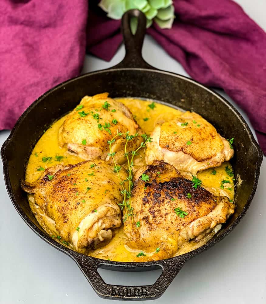 smothered pork chop thighs in a cast iron skillet with gravy