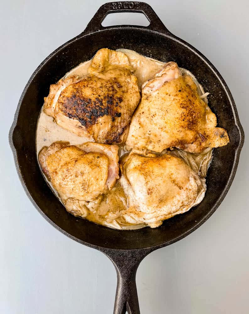 smothered pork chop thighs in a cast iron skillet with gravy