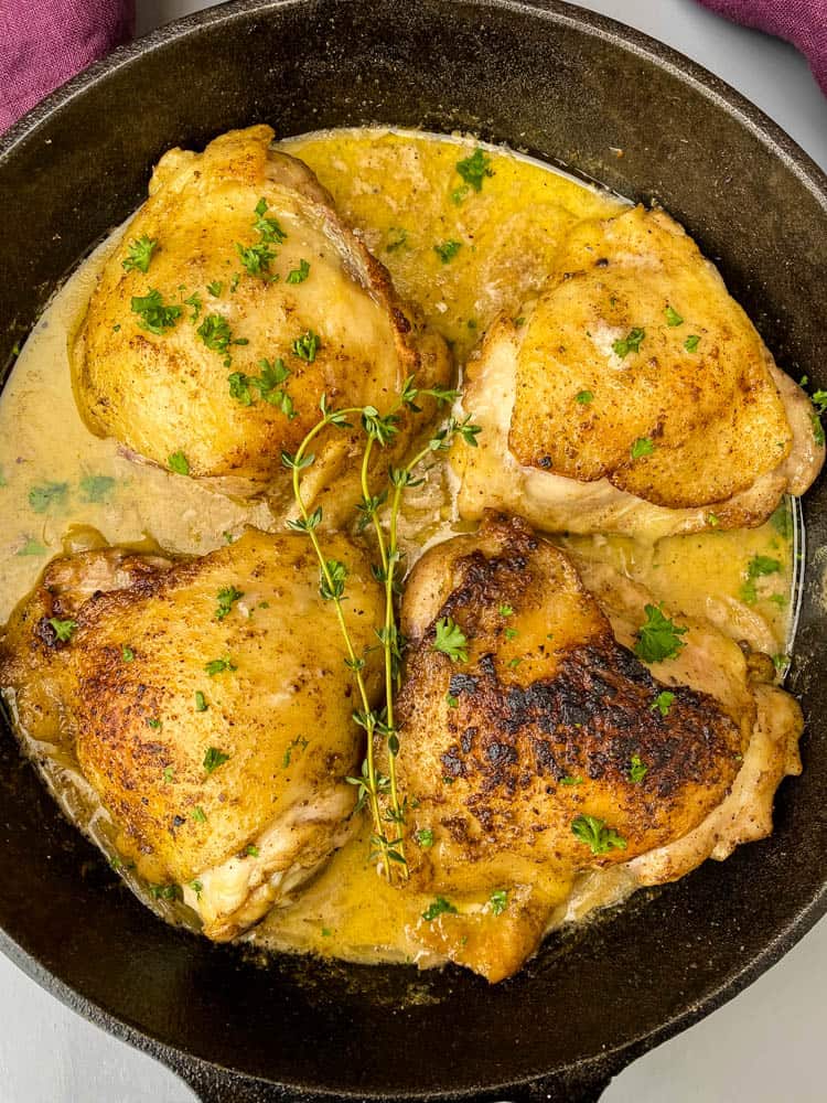 smothered pork chop thighs in a cast iron skillet with gravy