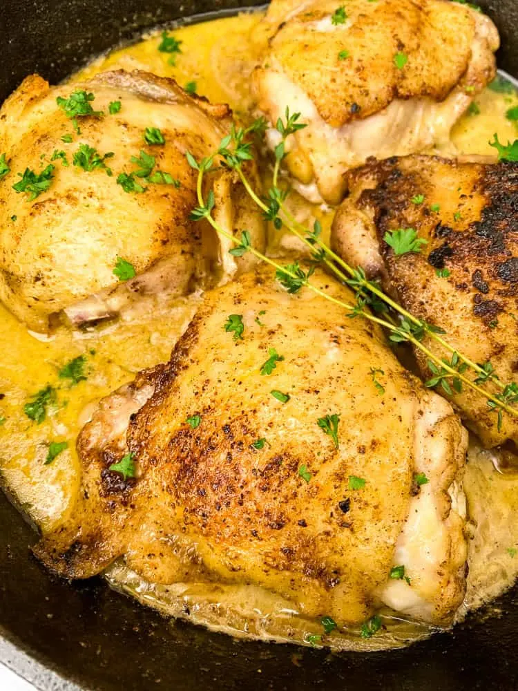 close up photo with smothered pork chop thighs in a cast iron skillet with gravy