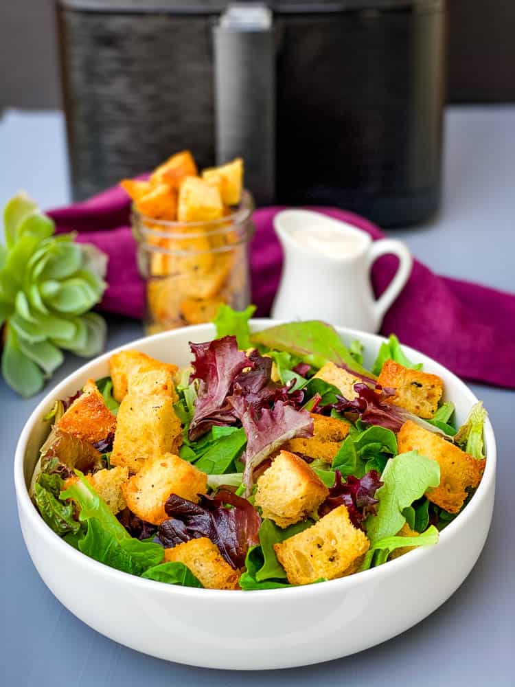 air fryer croutons on a salad in a white bowl